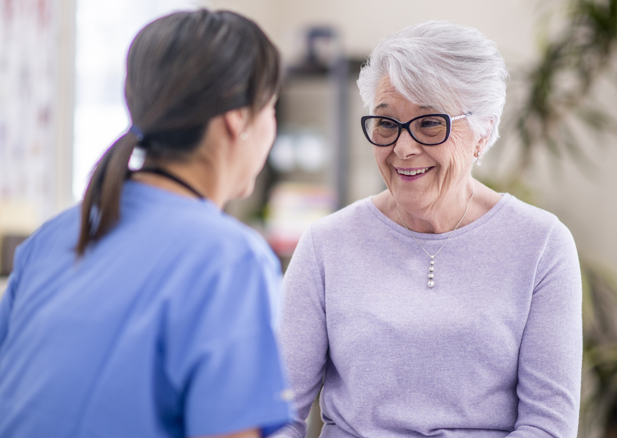 A senior woman talks to her doctor about some recent struggles she is going through. She looks very optimistic.