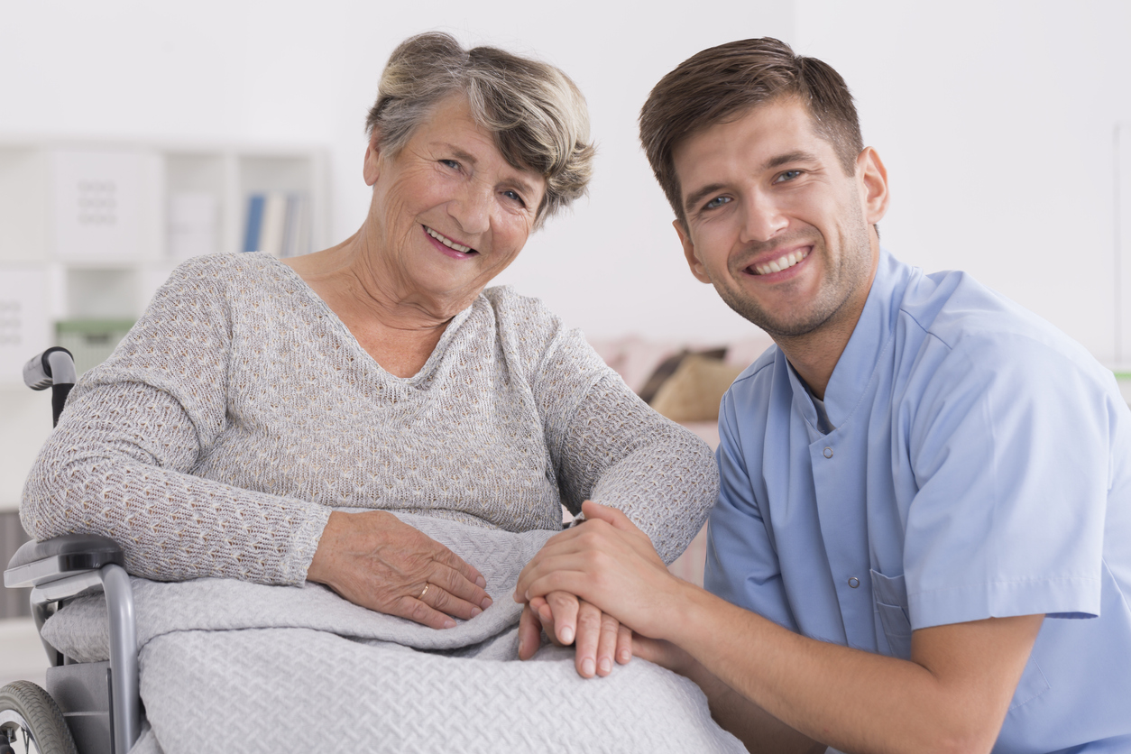 Happy elderly woman with male nurse in retirement home